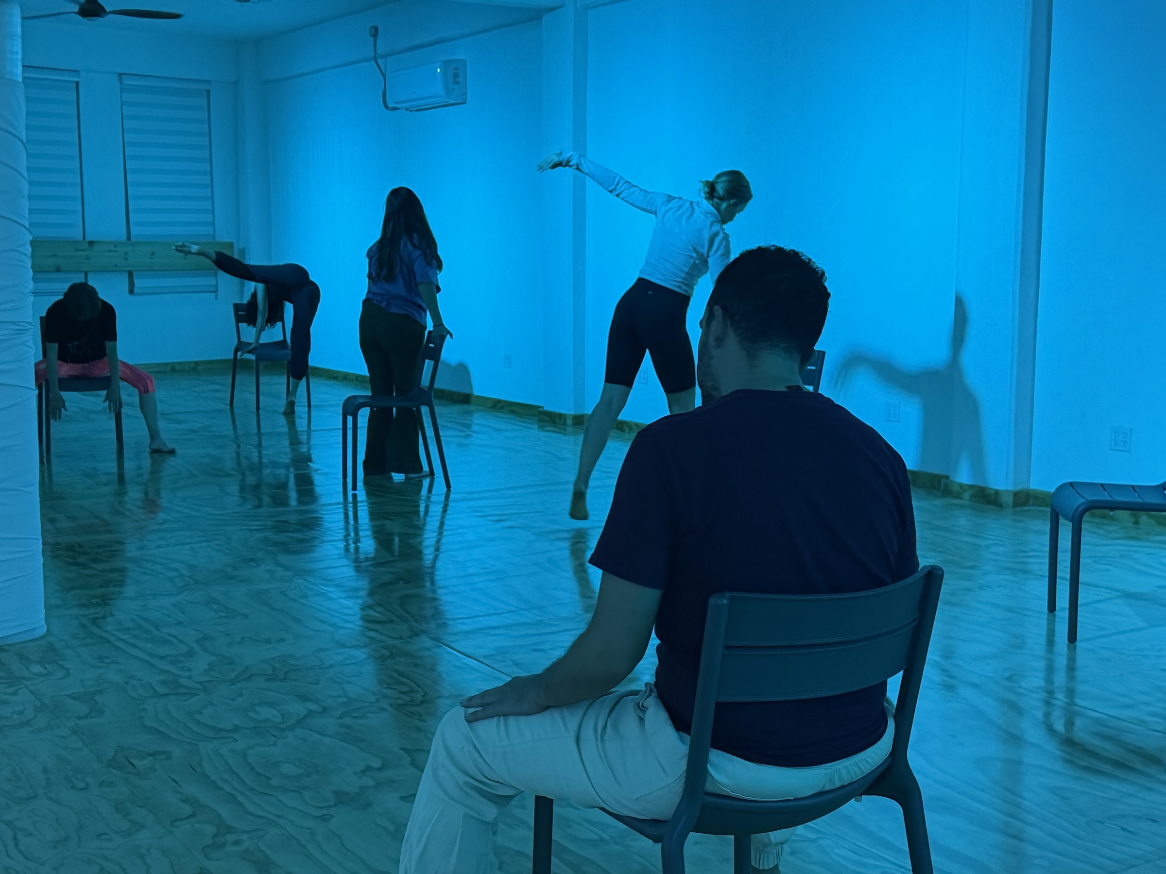 Sesión de danzaterapia en Centro RAM, La Paz: participantes exploran el movimiento con sillas bajo luz azul